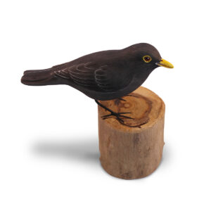 A wooden handcrafted Blackbird sat on a log by Shiny Happy Eco.