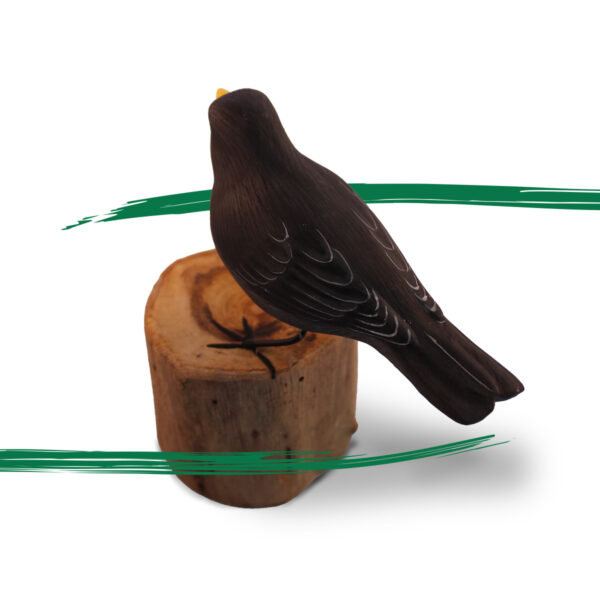 A wooden handcrafted Blackbird sat on a log by Shiny Happy Eco.