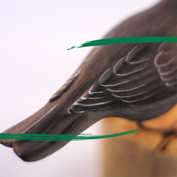 Close up of a wooden handcrafted Blackbird sat on a log by Shiny Happy Eco.