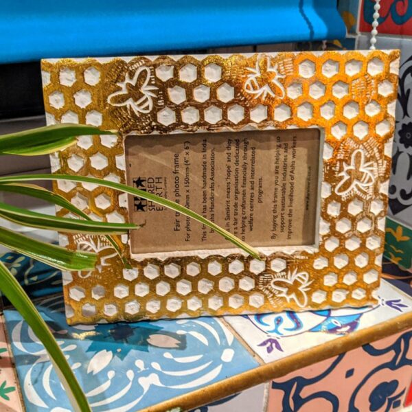 4 x 6 photo frame with honeycomb and bees design shown landscape on a shelf with a plant.