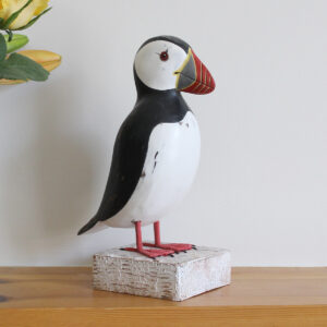 Wooden Puffin ornament on a shelf, hand made and painted in a rustic style and available from Shiny Happy Eco.