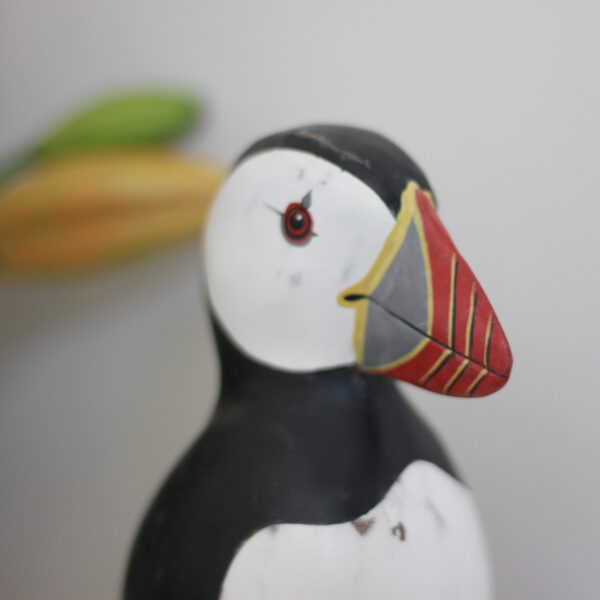 Close up of a Wooden Puffin ornament, hand made and painted in a rustic style and available from Shiny Happy Eco.