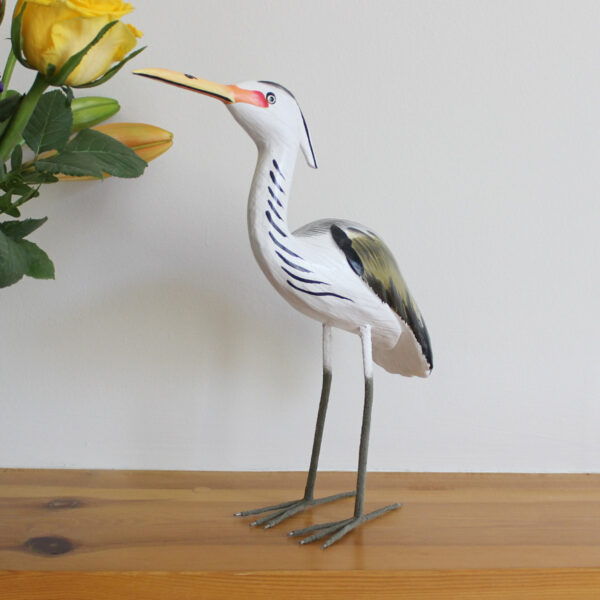 Wooden Heron ornament handmade and hand painted next to flowers on a mantlepiece available from Shiny Happy Eco.